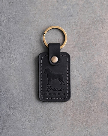 Black leather keychain debossed with a Cane Corso above the name Bruno and THE CORSO, on gray concrete