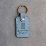 Turquoise leather keychain debossed with a mason jar above the words Canning SEASON, on gray concrete