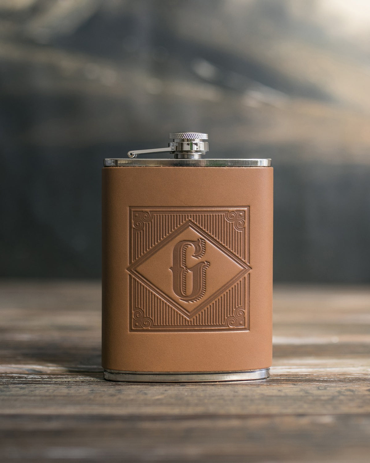 Caramel leather hip flask with an initial pressed into the diamond frame