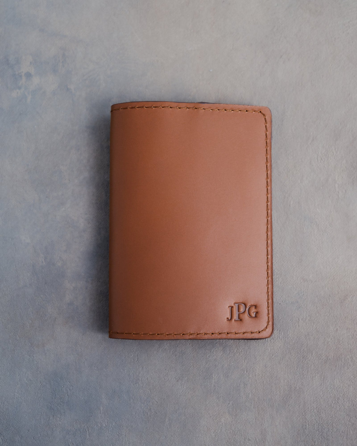 Caramel leather passport cover with the monogram JPG with the last initial large pressed into the bottom corner
