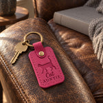 Fuchsia Cat Auntie keychain on a ring of keys beside a wrapped gift on a holiday table
