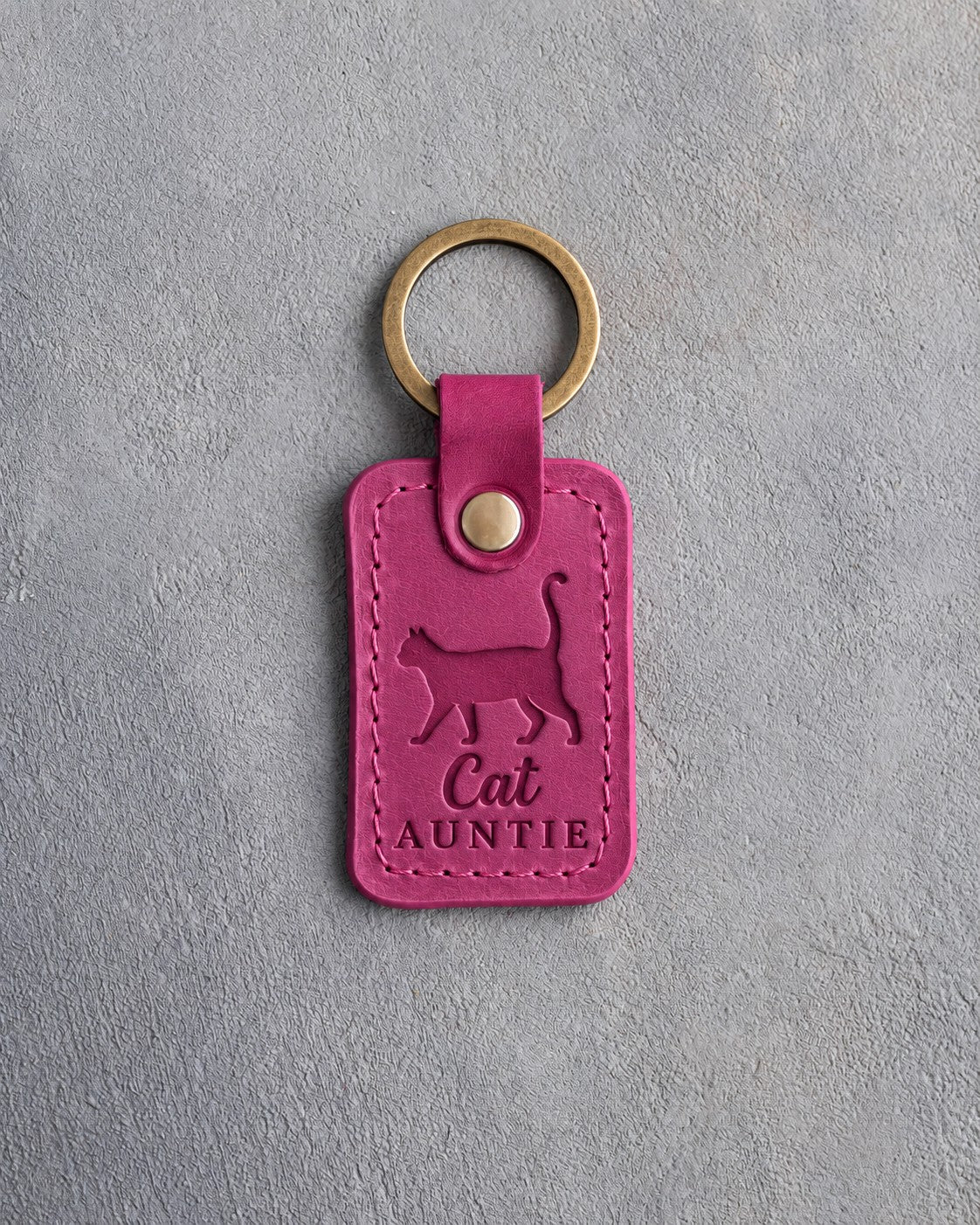 Fuchsia leather keychain debossed with a cat walking with its tail straight up above the words Cat AUNTIE