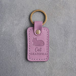 Lilac leather keychain debossed with a loafing cat, paws tucked under, above the words Cat GRANDMA