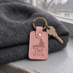 Blush Cat Mom keychain on a ring of house keys resting on a sunny windowsill