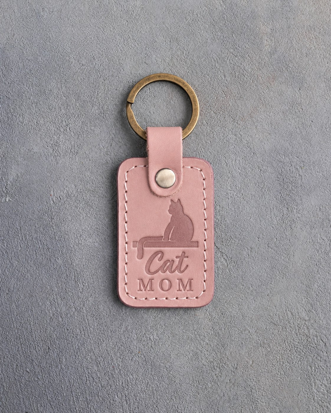 Blush pink leather keychain debossed with a cat sitting on a windowsill above the words Cat MOM