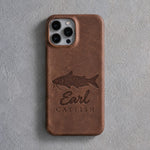 Back of a Sicilian brown leather iPhone case debossed with a channel catfish above Earl and CATFISH below the camera, on gray plaster