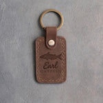 Sicilian brown leather keychain debossed with a channel catfish above Earl and CATFISH, on gray plaster