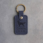 Blueberry navy leather keychain debossed with a Cavalier King Charles Spaniel silhouette and the words Cavalier DAD, on gray concrete