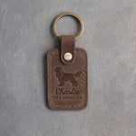 Sicilian brown leather keychain debossed with a Cavalier King Charles Spaniel silhouette, the name Charlie and THE CAVALIER, on gray concrete