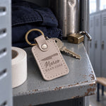Marco Head Chef keychain in pale gray leather on a stainless prep table beside a folded kitchen towel