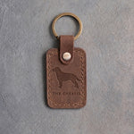 Sicilian brown leather keychain debossed with a Chesapeake Bay retriever above THE CHESSIE, on gray concrete