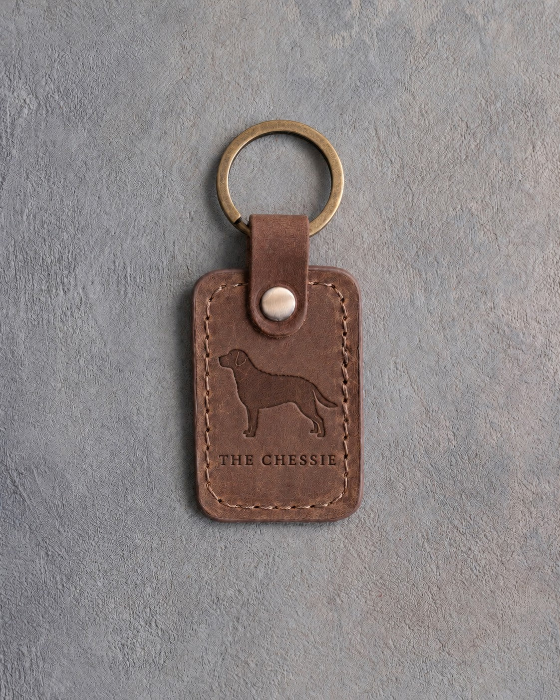 Sicilian brown leather keychain debossed with a Chesapeake Bay retriever above THE CHESSIE, on gray concrete