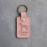 Blush pink leather keychain debossed with a Chesapeake Bay retriever and the words Chessie MOM, on gray concrete