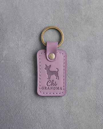 Lilac leather keychain debossed with a chihuahua silhouette and the words Chi GRANDMA, on gray concrete