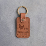 Caramel leather keychain debossed with a hen and two chicks above the words Chicken math IS REAL, on gray concrete