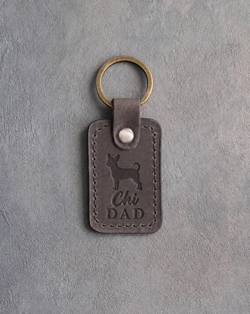Country gray leather keychain with a debossed chihuahua and Chi DAD lettering on gray concrete