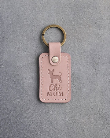 Blush pink leather keychain debossed with a chihuahua silhouette and the words Chi MOM, on gray concrete