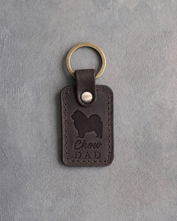 Dark espresso leather keychain debossed with a Chow Chow silhouette and the words Chow DAD, on gray concrete