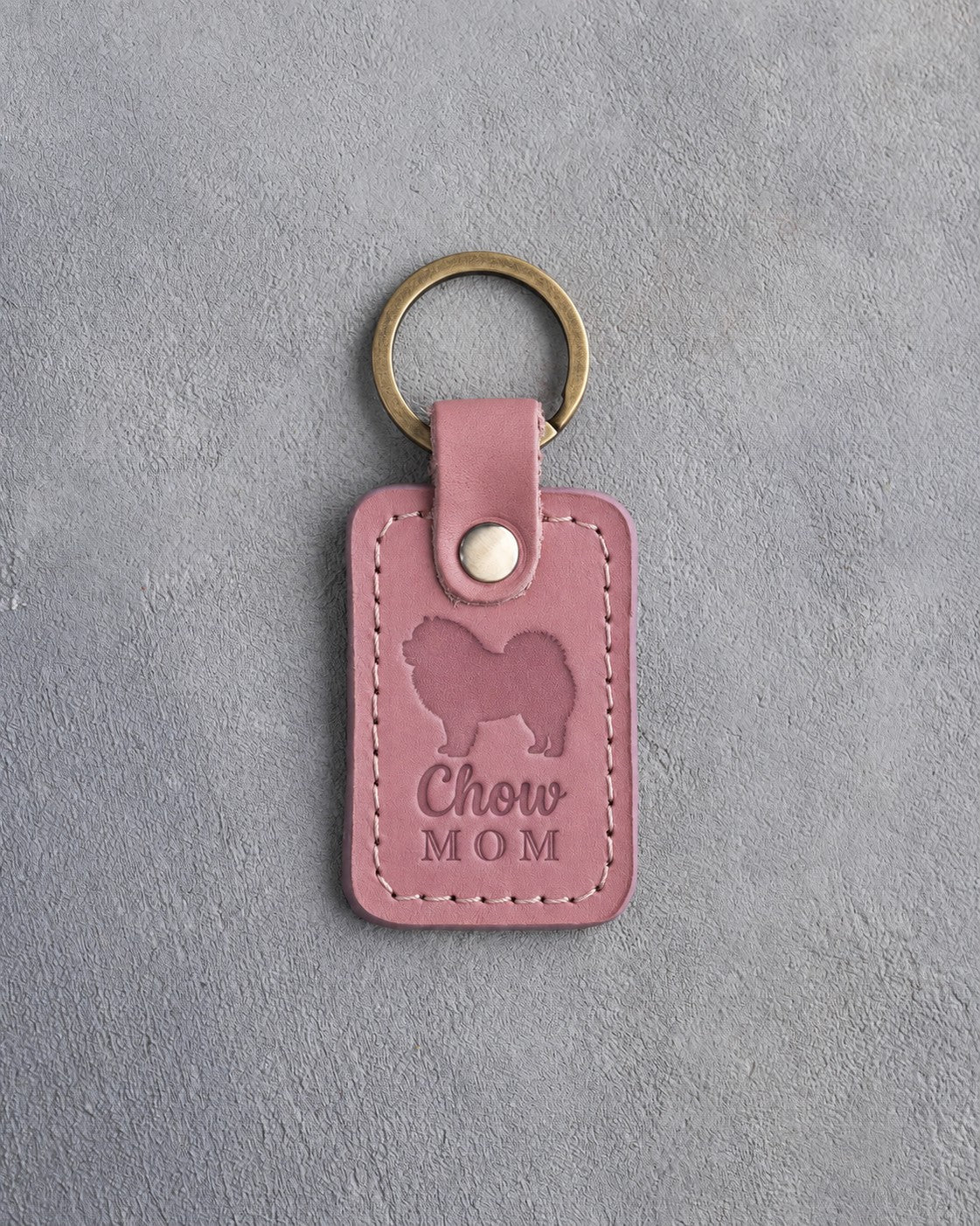 Parisian Blossom pink leather keychain debossed with a Chow Chow silhouette and the words Chow MOM, on gray concrete
