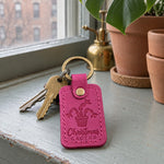 Fuchsia Christmas Cactus keychain on a windowsill beside a blooming pink Christmas cactus in a clay pot