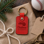 Red Christmas Coach keychain on brown kraft paper beside a fir sprig and a blank kraft gift tag