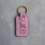 Lilac leather keychain with a debossed cocker spaniel and the words Cocker MOM, on gray concrete