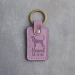 Lilac leather keychain debossed with a Coonhound silhouette and the words Hound MOM, on gray concrete