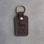 Dark espresso leather keychain debossed with a corgi silhouette and the words Corgi DAD, on gray concrete