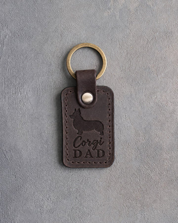 Dark espresso leather keychain debossed with a corgi silhouette and the words Corgi DAD, on gray concrete