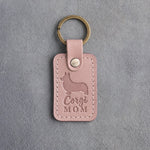 Blush pink leather keychain with a debossed Pembroke corgi silhouette and Corgi MOM lettering on gray concrete