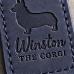 Close-up of Winston and THE CORGI debossed in navy full-grain leather below a tailless corgi silhouette