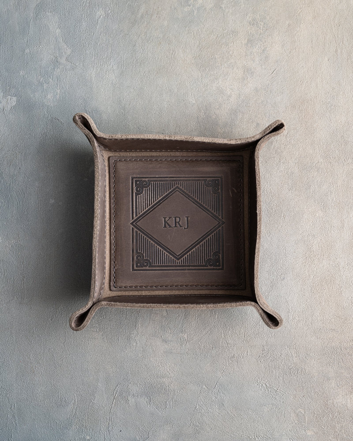 Country Gray leather valet tray with snapped corners and the initials KRJ pressed into the diamond frame, seen from above