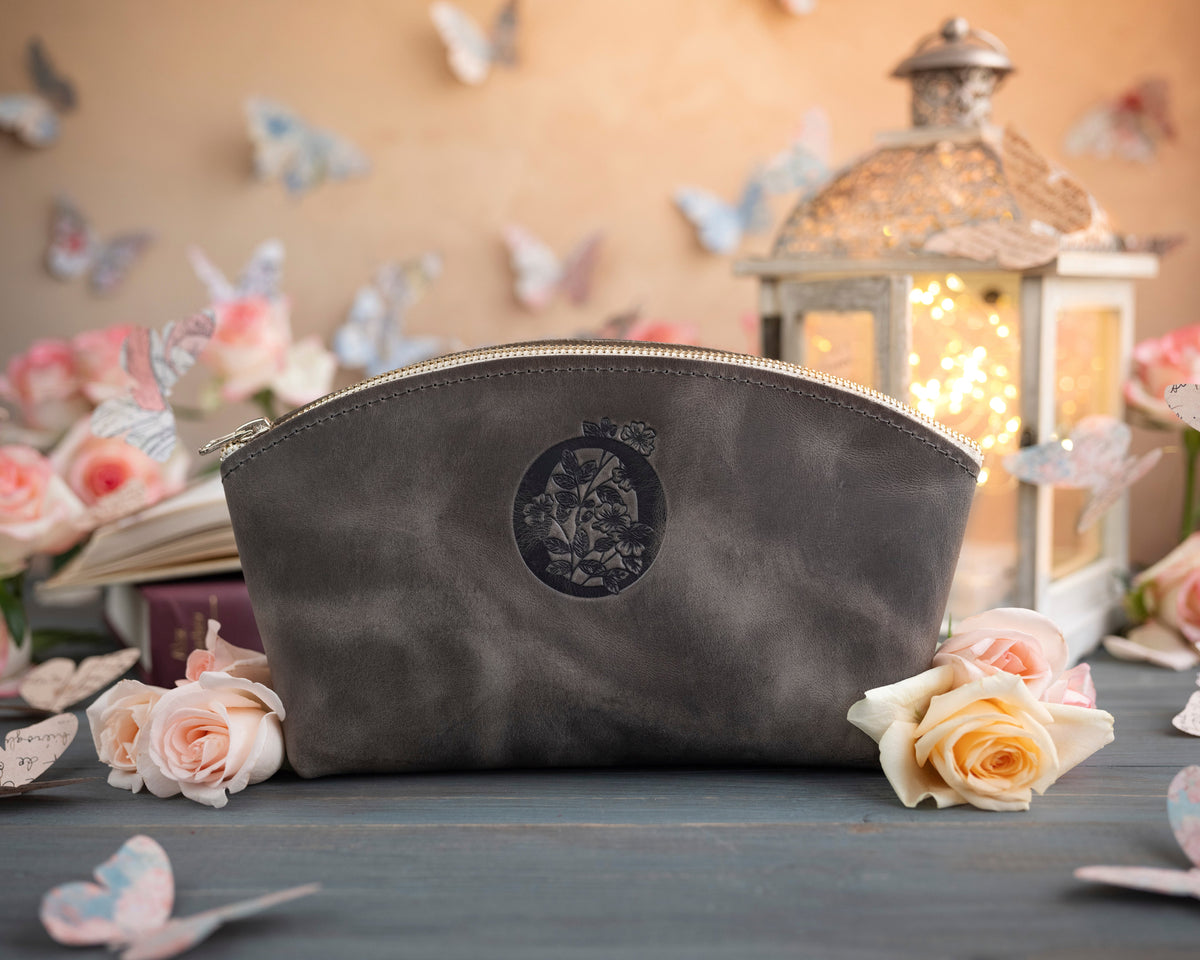 Country gray leather makeup bag with a floral monogram deboss, roses and a lit lantern in the background