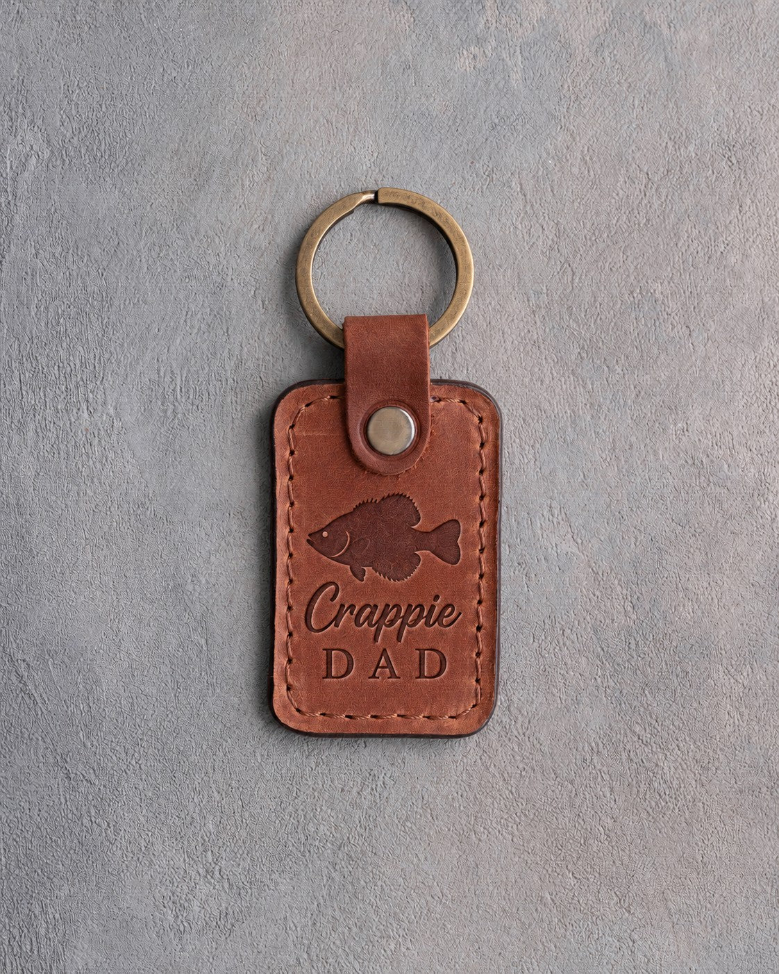 Arizona leather keychain debossed with a crappie above the words Crappie DAD, on gray plaster