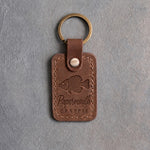 Sicilian brown leather keychain debossed with a crappie above Papermouth and CRAPPIE, on gray concrete