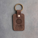 Sicilian brown leather keychain debossed with a vinyl record above the words Crate DIGGER, on gray plaster