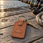 Caramel Garrett TIGHT LINES keychain in full-grain leather on sun-bleached dock boards beside a spinning rod in low evening sun