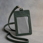 Forest Green leather badge holder with ID window and matching lanyard, debossed with a sample business logo, on grey plaster