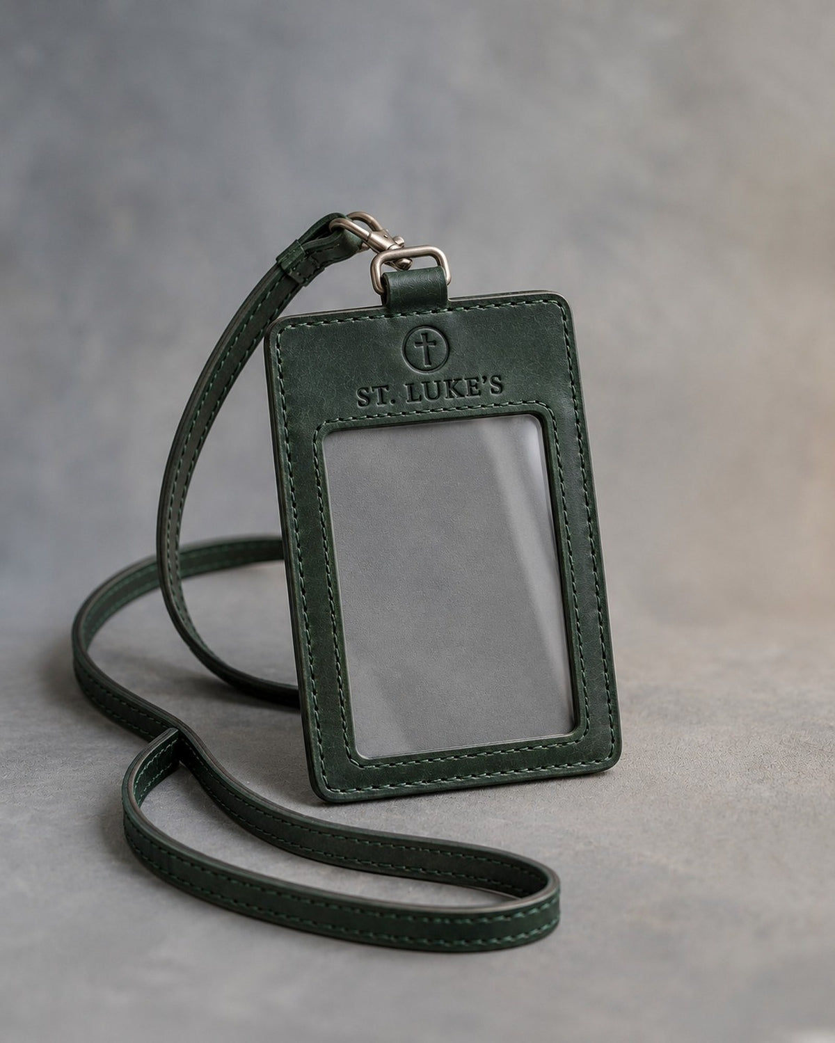 Forest Green leather badge holder with ID window and matching lanyard, debossed with a sample business logo, on grey plaster