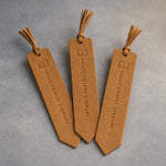 Indian Summer leather bookmarks with tassels debossed with a sample business logo, on a grey plaster backdrop
