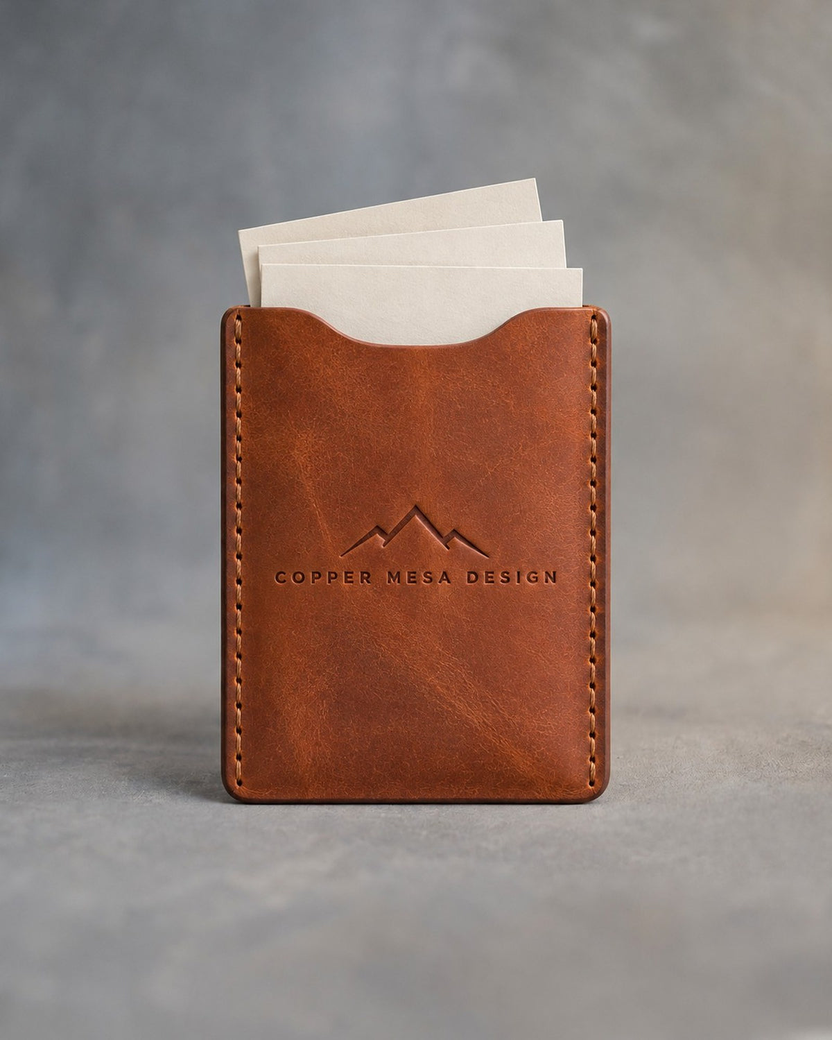 Arizona leather business card holder debossed with a sample business logo, on a grey plaster backdrop