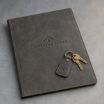 Country Gray leather closing folder and keychain debossed with a sample business logo, on a grey plaster backdrop