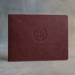 Sangria leather diploma cover debossed with a sample business logo, on a grey plaster backdrop