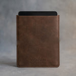Sicilian Brown leather tablet sleeve debossed with a sample business logo, on a grey plaster backdrop