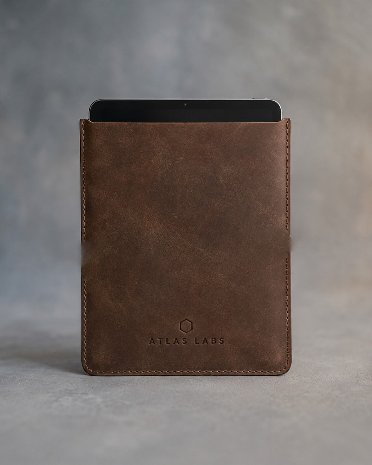 Sicilian Brown leather tablet sleeve debossed with a sample business logo, on a grey plaster backdrop