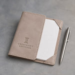 Gray Sand leather notepad holder debossed with a sample business logo, on a grey plaster backdrop
