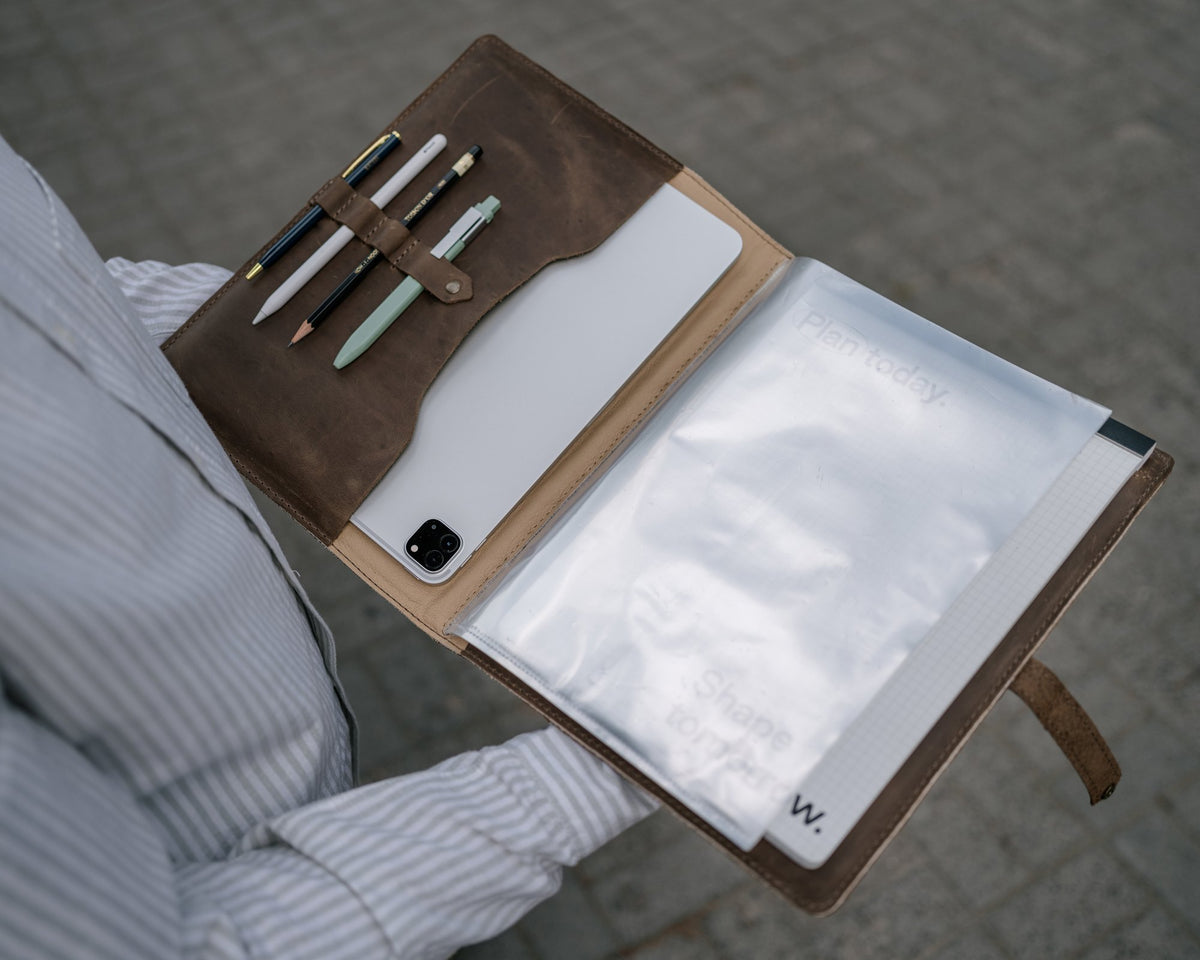 Open leather padfolio with a tablet in the left pocket, clear sheet-protector pages and a letter-size notebook