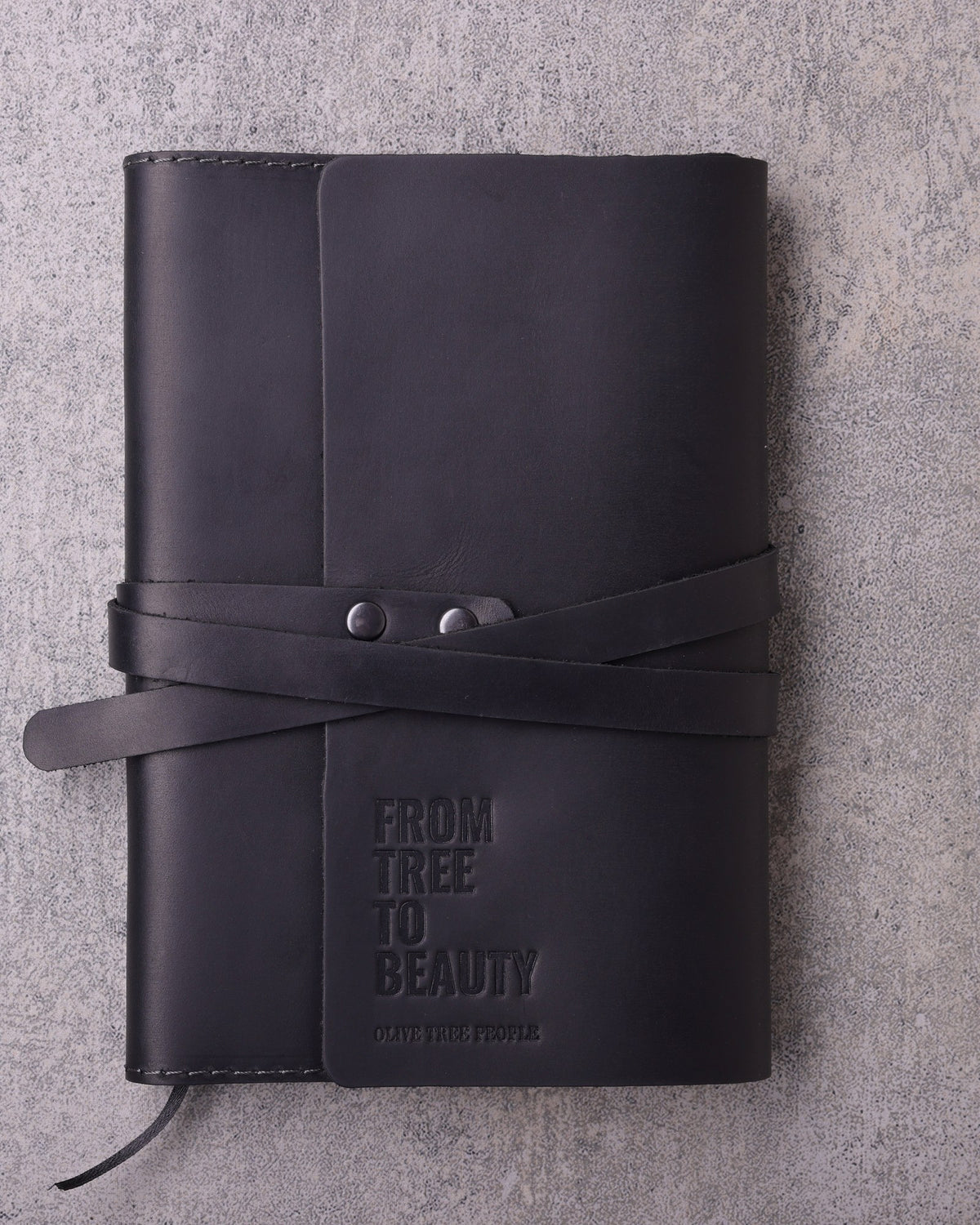 Black leather wrap journal debossed with the Olive Tree People logo, seen from above