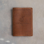 Sicilian Brown leather passport cover with a sample travel agency logo, AURORA TRAVEL CO., pressed into the front, on grey plaster