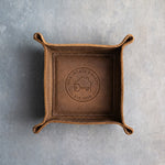 Sicilian Brown leather valet tray with a sample realty logo, NORTHGATE REALTY EST. 2009, pressed into the base, on grey plaster